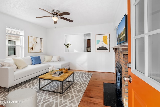 living room with ceiling fan, a textured ceiling, and wood finished floors