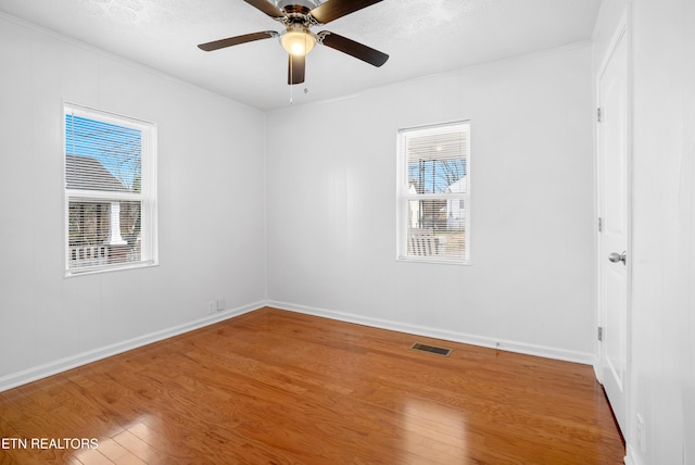 interior space with ornamental molding, visible vents, multiple windows, and wood finished floors