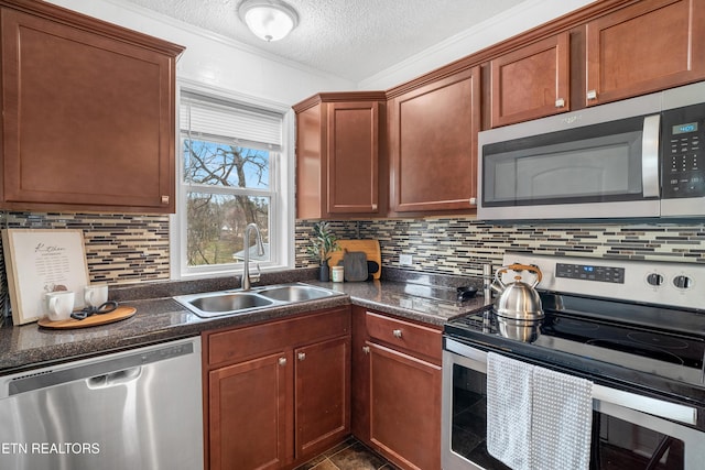 kitchen with a textured ceiling, appliances with stainless steel finishes, dark countertops, and a sink