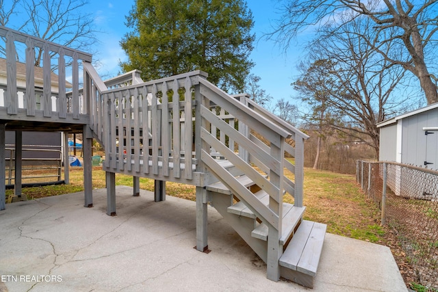 view of community featuring fence, a patio, a wooden deck, and stairs