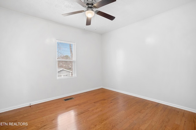 empty room featuring ornamental molding, baseboards, visible vents, and light wood finished floors