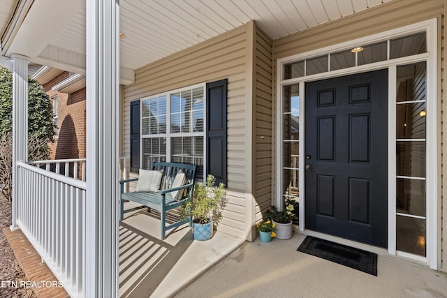 view of exterior entry with a porch and brick siding