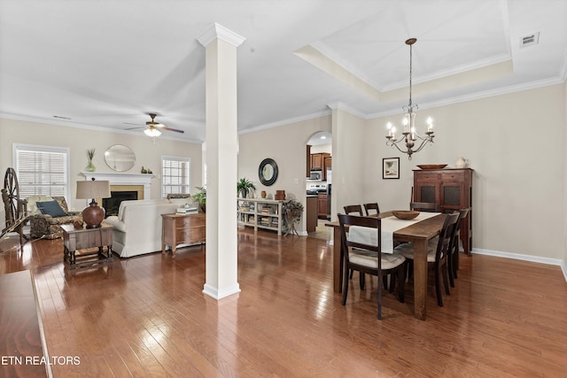 dining space with dark wood-style floors, a healthy amount of sunlight, a fireplace, and ornate columns