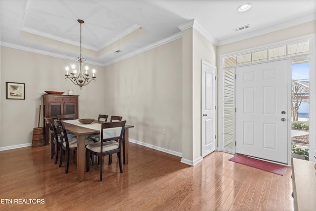 dining area featuring a raised ceiling, a notable chandelier, baseboards, and wood finished floors