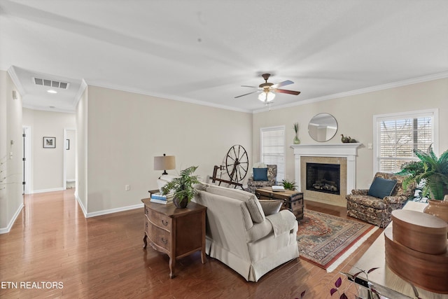 living room featuring visible vents, crown molding, baseboards, and wood finished floors