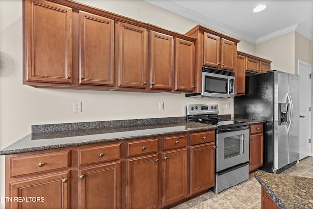 kitchen with dark stone counters, appliances with stainless steel finishes, brown cabinetry, and crown molding