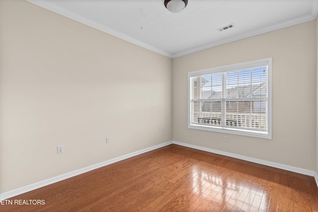 unfurnished room featuring visible vents, crown molding, baseboards, and wood finished floors