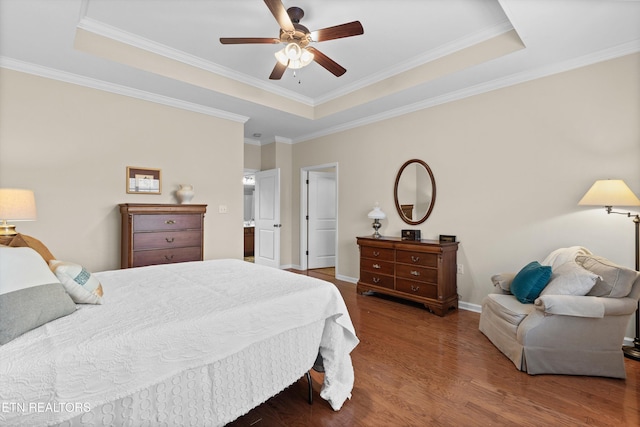 bedroom featuring a tray ceiling, crown molding, baseboards, and wood finished floors