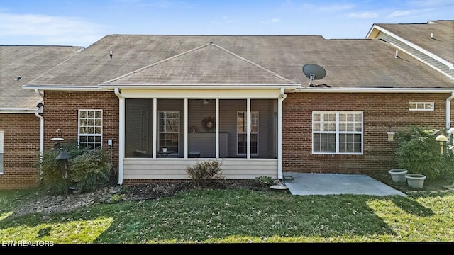 rear view of property with a sunroom, a patio area, a yard, and brick siding