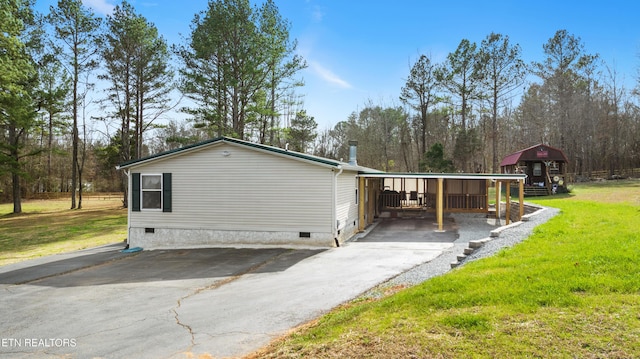 view of side of property featuring aphalt driveway, crawl space, and a lawn