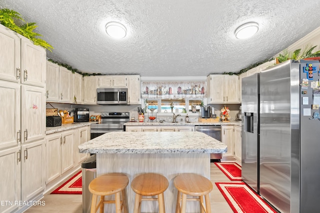 kitchen with appliances with stainless steel finishes, a kitchen island, light wood-style flooring, and a breakfast bar area