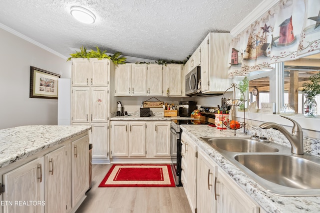 kitchen featuring a textured ceiling, a sink, appliances with stainless steel finishes, ornamental molding, and light wood finished floors