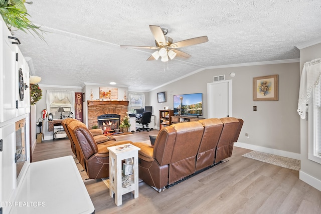 living area featuring lofted ceiling, light wood-style flooring, visible vents, a brick fireplace, and crown molding