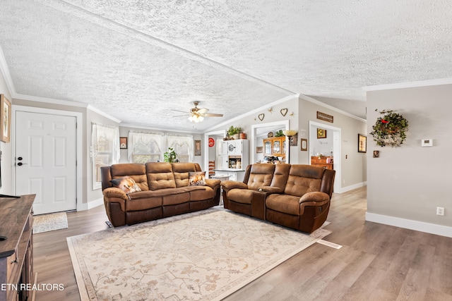 living area with crown molding, a textured ceiling, baseboards, and wood finished floors