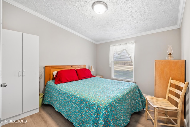 bedroom featuring a textured ceiling, ornamental molding, and wood finished floors