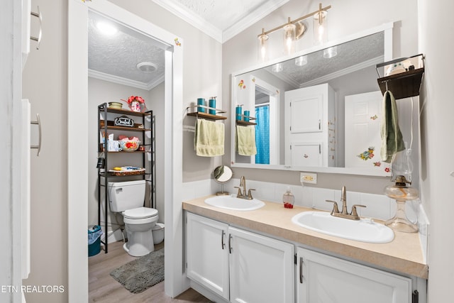 full bathroom with a textured ceiling, ornamental molding, a sink, and toilet