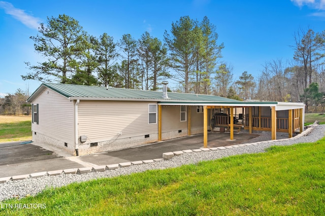 rear view of house with crawl space, a lawn, metal roof, and an attached carport