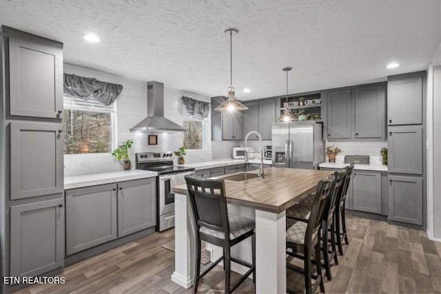 kitchen featuring island exhaust hood, appliances with stainless steel finishes, dark wood-type flooring, and gray cabinetry