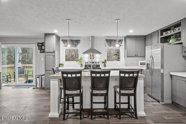 kitchen featuring stainless steel appliances, wall chimney range hood, a center island, and gray cabinetry