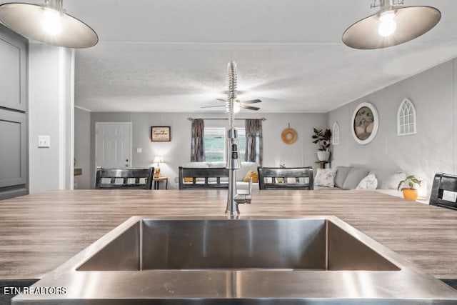 kitchen featuring a ceiling fan, open floor plan, light countertops, a textured ceiling, and a sink