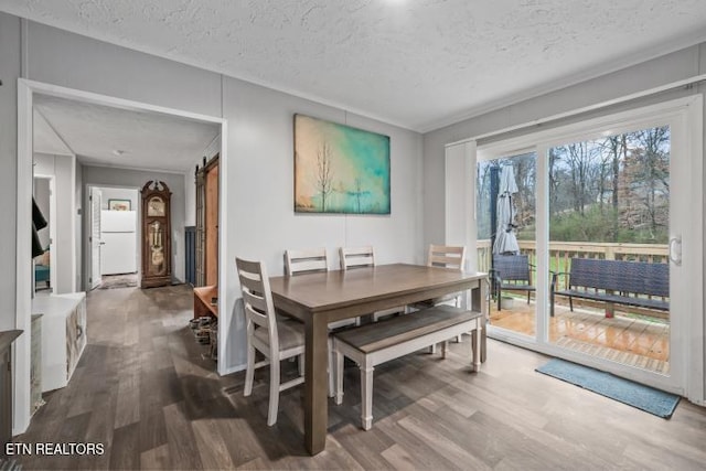 dining space with a textured ceiling, a barn door, and wood finished floors