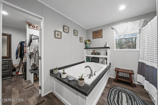 bathroom featuring a garden tub, wood finished floors, and visible vents