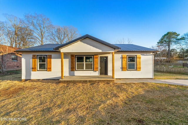 view of front of house featuring metal roof, a porch, fence, a standing seam roof, and a front yard