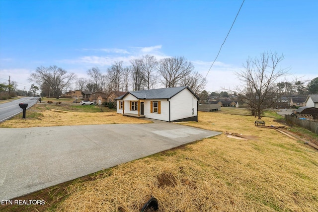 exterior space with metal roof, a front lawn, and fence