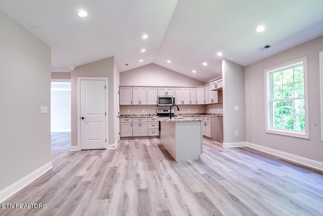 kitchen featuring light stone counters, visible vents, white cabinets, appliances with stainless steel finishes, and an island with sink