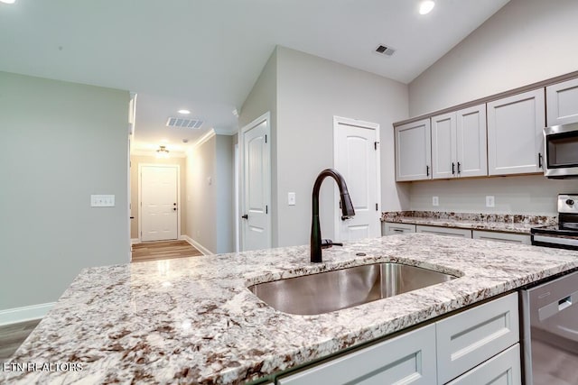 kitchen featuring light stone countertops, visible vents, stainless steel appliances, and a sink