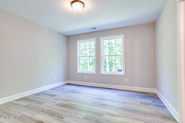 unfurnished room featuring light wood-style floors, visible vents, and baseboards