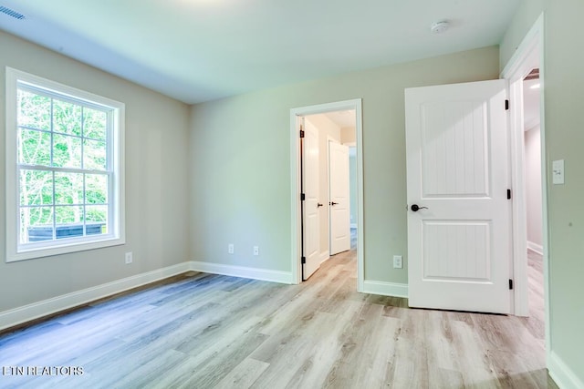 unfurnished bedroom featuring light wood finished floors, visible vents, and baseboards