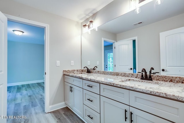 full bath featuring double vanity, visible vents, a sink, and wood finished floors