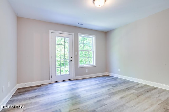 doorway to outside with light wood-style floors, visible vents, and baseboards