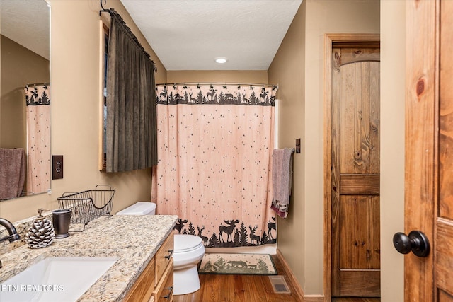 full bathroom with baseboards, visible vents, toilet, wood finished floors, and vanity