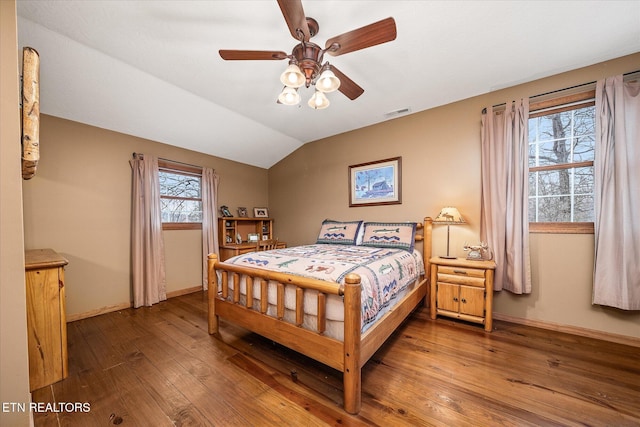 bedroom with vaulted ceiling, wood finished floors, visible vents, and baseboards