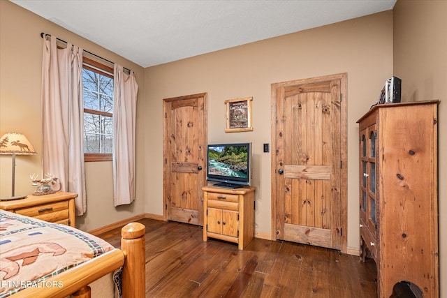 bedroom featuring baseboards and dark wood-type flooring