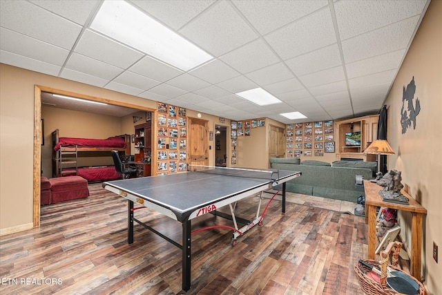 rec room with a drop ceiling, wood finished floors, and baseboards