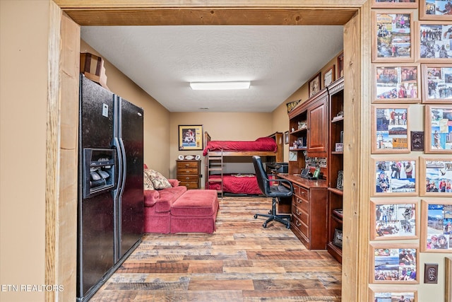 office space featuring light wood-style flooring, a textured ceiling, and built in study area