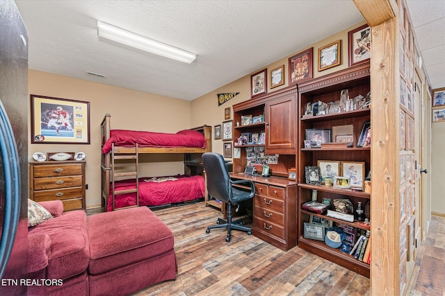 office space with a textured ceiling, visible vents, and light wood-style floors