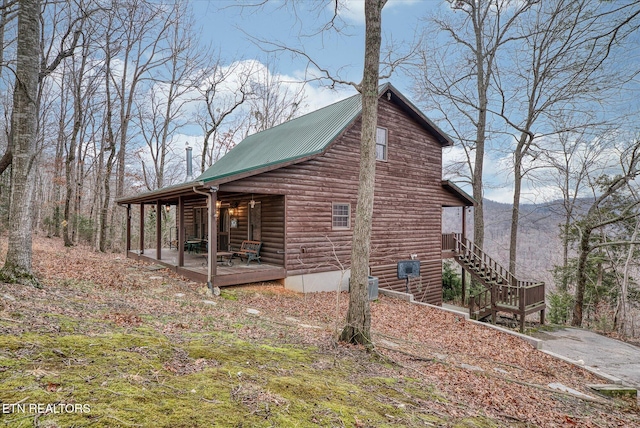 view of property exterior with covered porch, stairway, metal roof, and log veneer siding