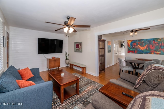 living room with light wood-style flooring, a ceiling fan, and baseboards