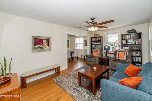 living area featuring a ceiling fan, baseboards, and wood finished floors