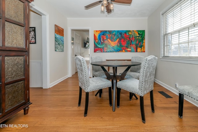 dining space with light wood finished floors, baseboards, visible vents, ceiling fan, and ornamental molding