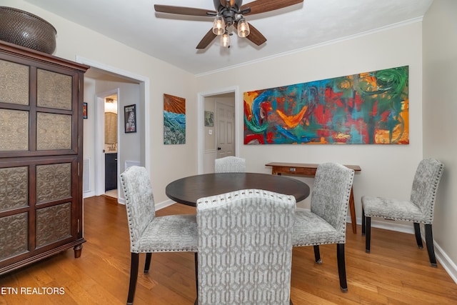 dining space featuring crown molding, ceiling fan, baseboards, and wood finished floors