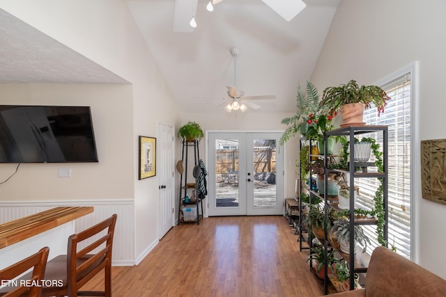 entrance foyer with a ceiling fan, a wainscoted wall, wood finished floors, vaulted ceiling, and french doors