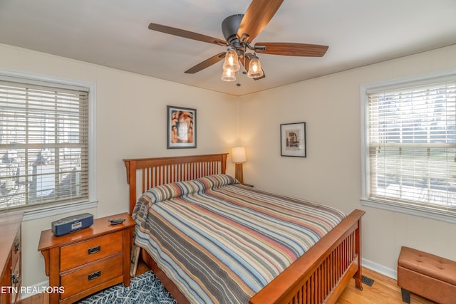 bedroom featuring ceiling fan, multiple windows, and light wood-style floors