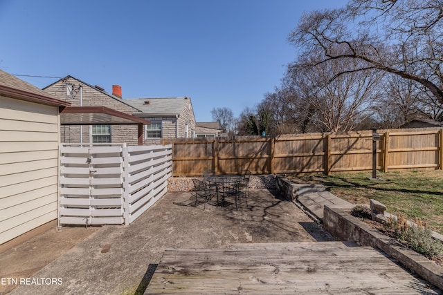 view of yard featuring a fenced backyard, a wooden deck, and outdoor dining space