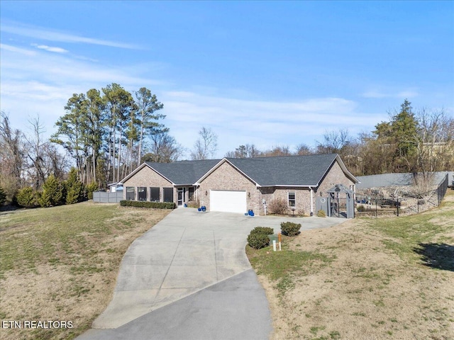 ranch-style home featuring an attached garage, brick siding, fence, driveway, and a front yard