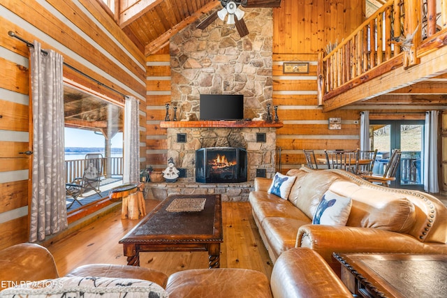 living area featuring a stone fireplace, wood walls, and light wood-style floors